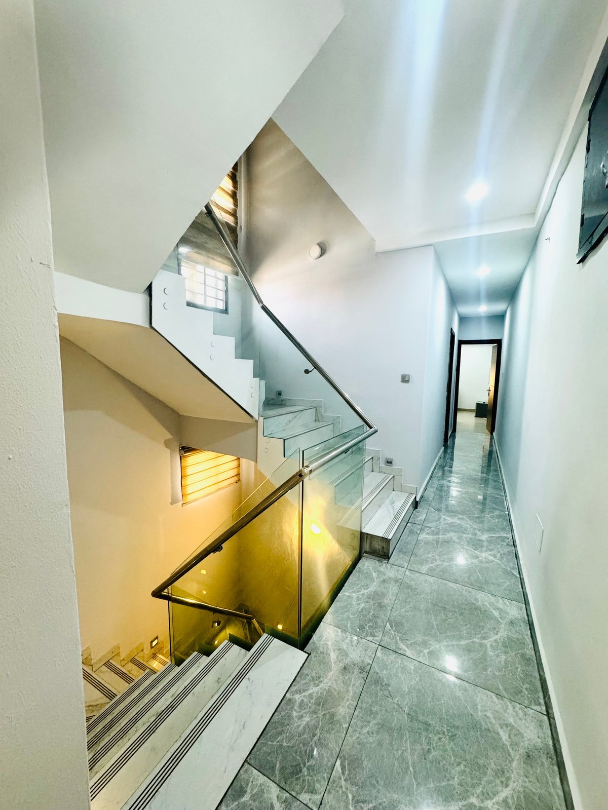 Modern stairwell with glass railing and gray tile flooring