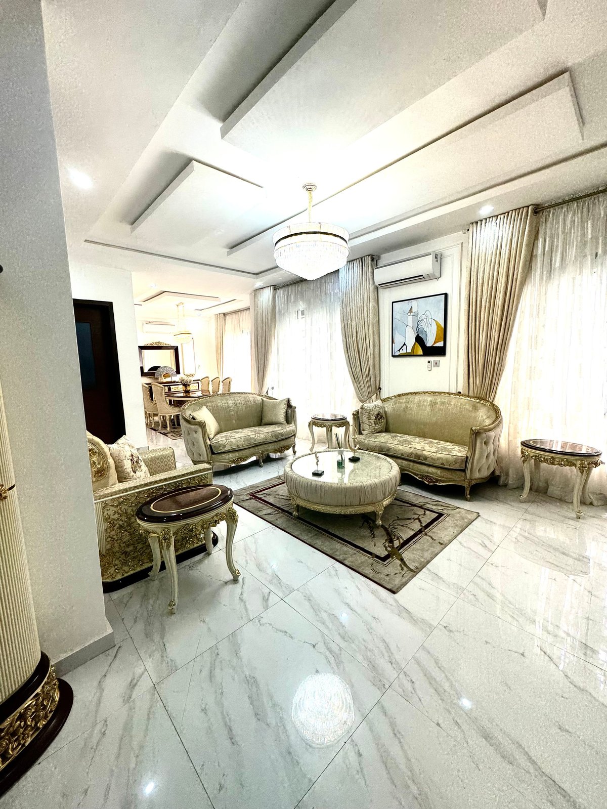 Luxurious living room with cream upholstered seating, marble floors and coffered ceiling