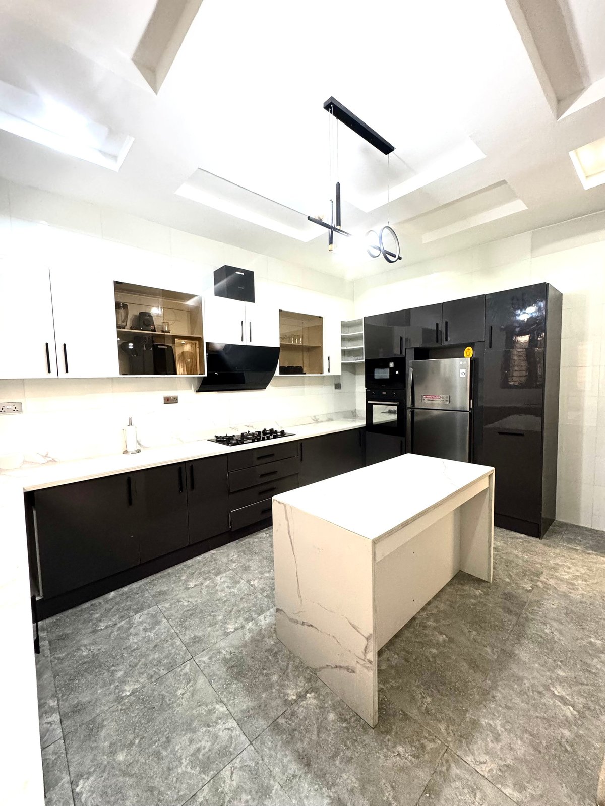 Modern black and white kitchen with island, built-in appliances and skylight ceiling