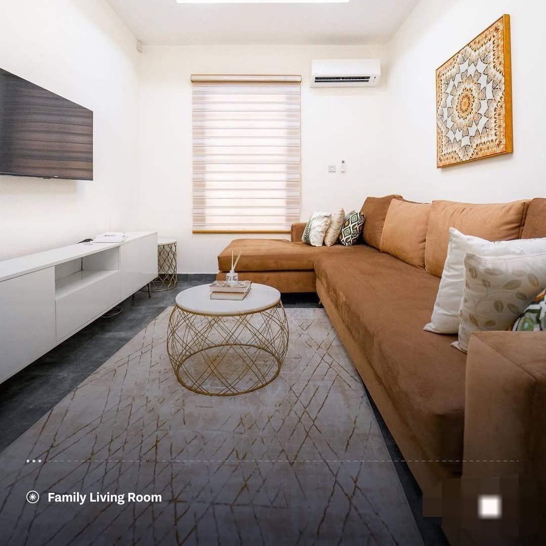 Family living room with tan sofa, flat-screen TV, marble coffee table and patterned rug
