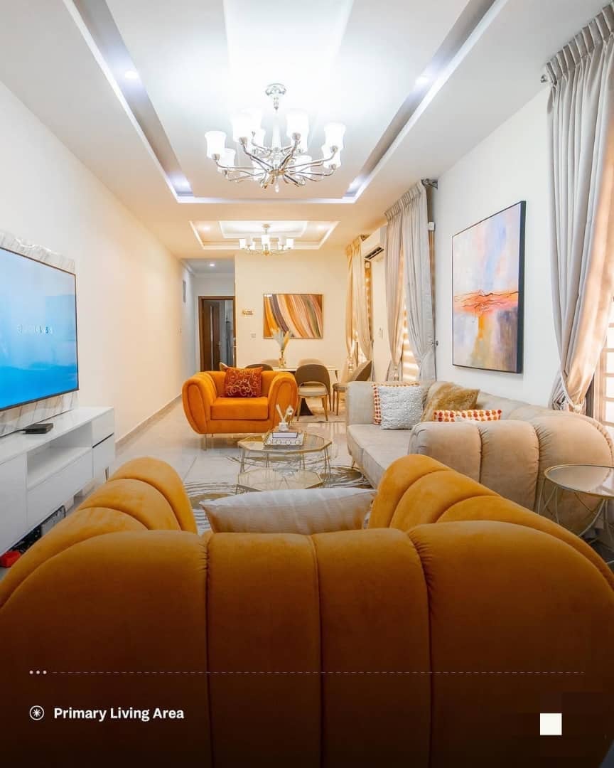 Primary living area with gold and beige furnishings and contemporary chandelier